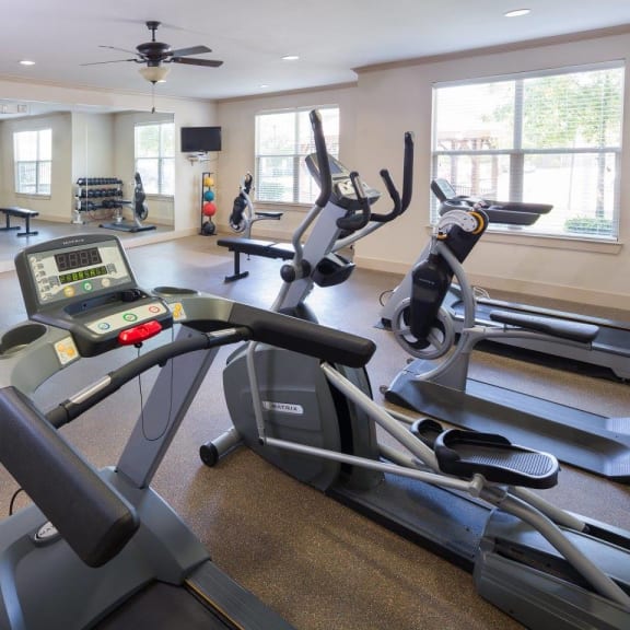 a gym with various machines and a ceiling fan