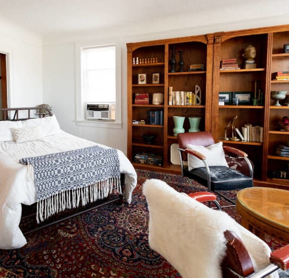 a bedroom with a bed and bookshelves     and a chair