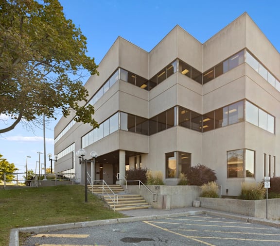 A modern building with a symmetrical design and a parking lot in front.