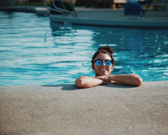 a woman with a straw hat laying by a pool