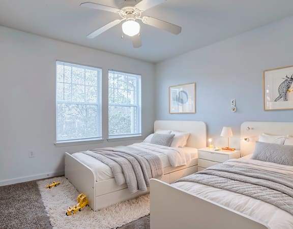 a bedroom at Beecher Terrace apartments with two windows and a bed with white sheets and pillows