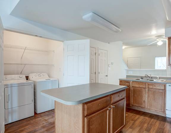 a living room with a couch and a dining table and a refrigerator surrounded by cabinets