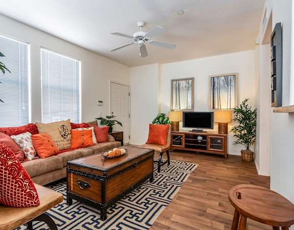 a living room with a couch and a dining table and a refrigerator surrounded by cabinets