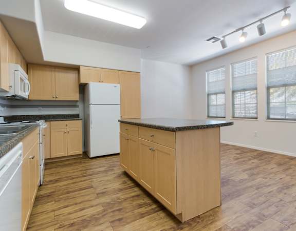 a living room with a couch and a dining table and a refrigerator surrounded by cabinets