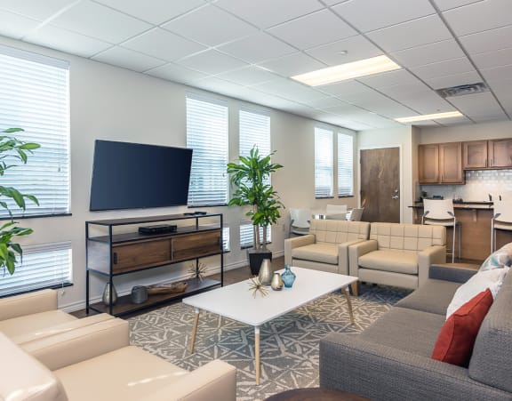 a living room with a couch and a dining table and a refrigerator surrounded by cabinets
