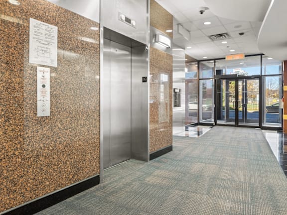 A hallway with a metal elevator and a sign on the wall.