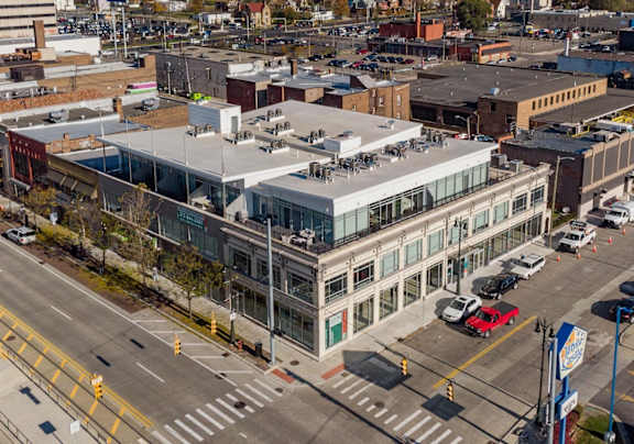 A large building with a glass facade is situated in the middle of a busy intersection.