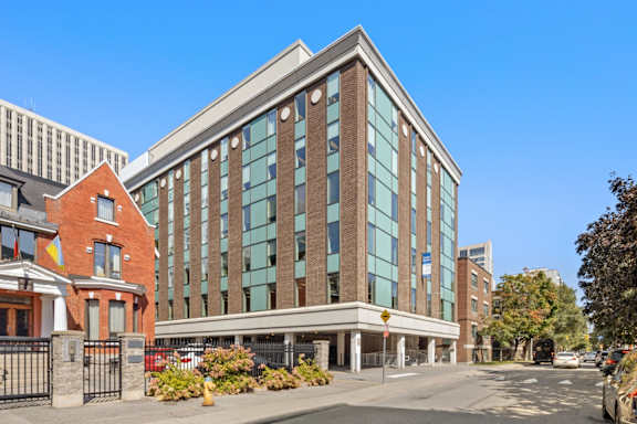 A modern glass building is situated in front of a red brick building.