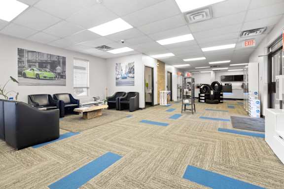 A spacious room with a car poster on the wall and a blue exit sign.