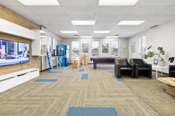 A room with a carpeted floor and a television on the wall.