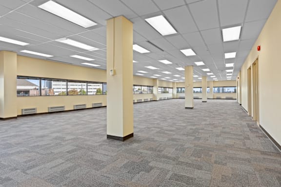A large, empty room with carpeted floors and columns.