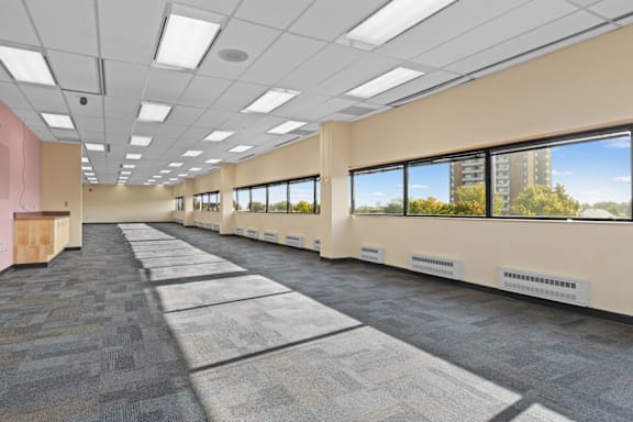 A long hallway with carpeted floors and windows on one side.
