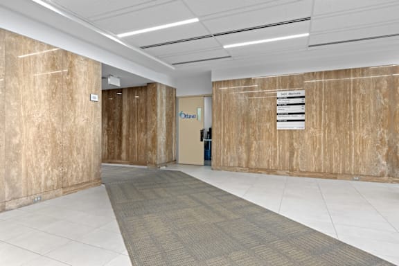 A hallway with a carpeted floor and a sign on the wall.