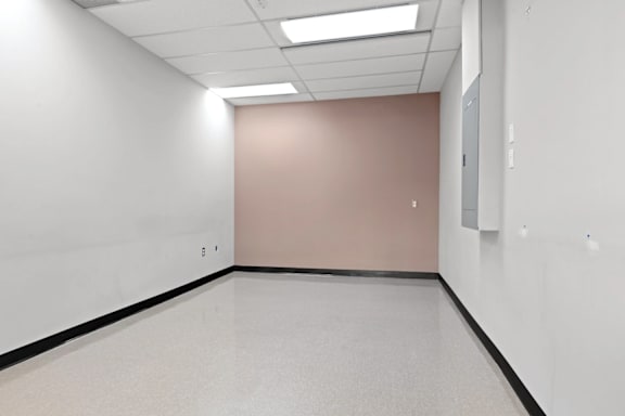 A room with white walls and a pink wall with a door.