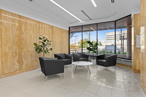 A modern office waiting area with black chairs and a wooden wall.