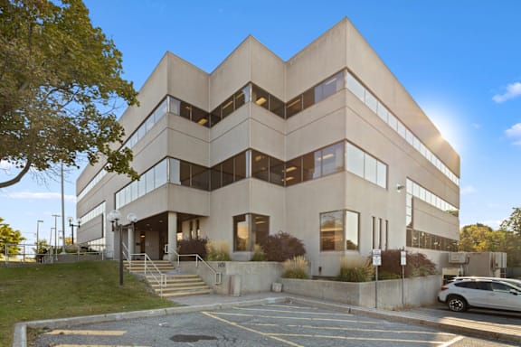 A modern building with a symmetrical design and a parking lot in front.