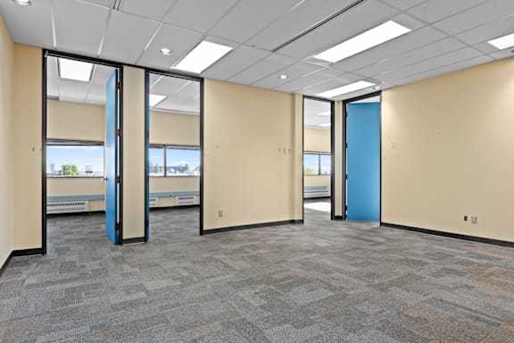 A room with a carpeted floor, a white ceiling, and a blue door.