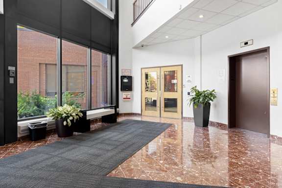 A hallway with a black carpet and a brown door.