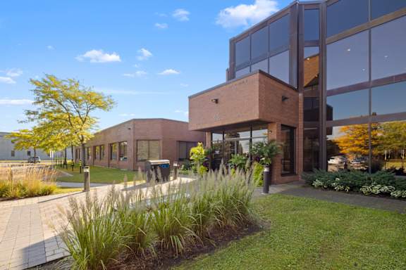 A modern building with a glass facade and a landscaped front yard.