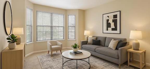 A living room with a grey couch, a white coffee table, and a large mirror on the wall.