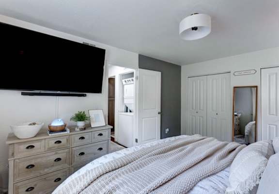 a bedroom with a bed and a dresser with a television on the wall
