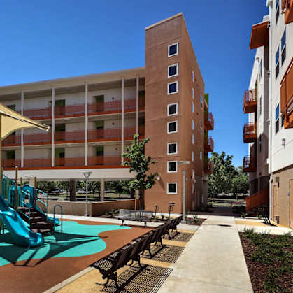 A playground with a slide and a bench in front of a building.
