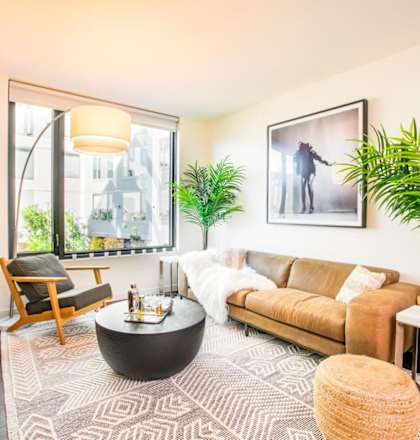 A living room with a brown couch, a coffee table, and a large window. at Ansel, San Francisco, 94103