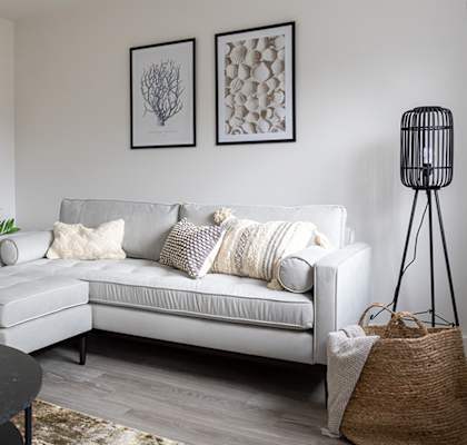 A living room with a white couch, a black table, and two framed pictures on the wall.