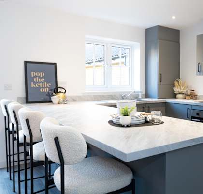 A kitchen with a marble countertop and grey cabinets.