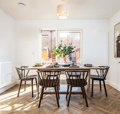 A dining room with a table set for six with a view of the street outside.