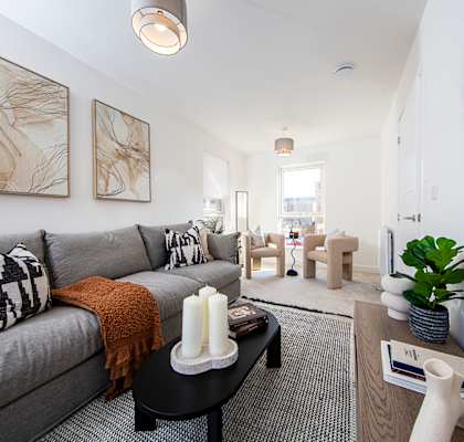 A living room with a grey couch and a large mirror on the wall.