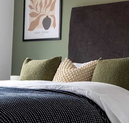 a bedroom with a bed with pillows and a picture on the wall