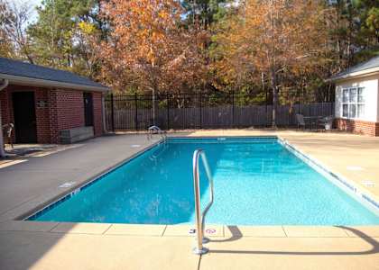 a swimming pool in front of a house with a black fence