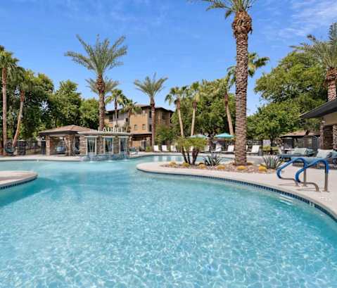 A large swimming pool surrounded by palm trees and lounge chairs. at The Laurel Apartments, Chandler