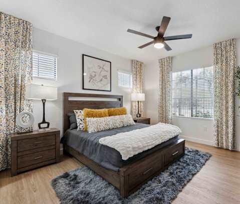 A bedroom with a bed, nightstands, and a ceiling fan. at The Laurel Apartments, Chandler