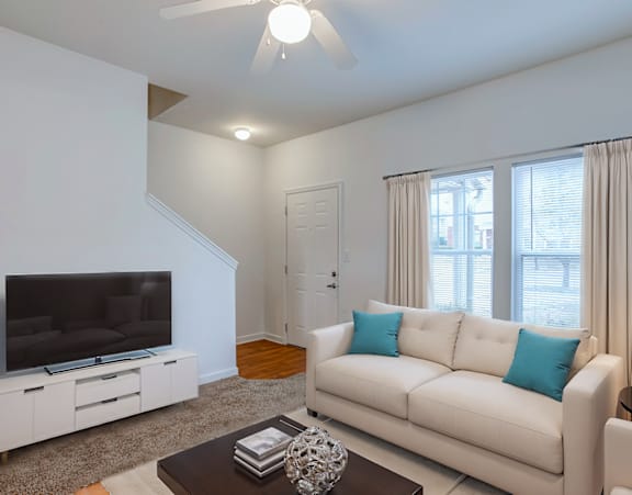 a living room with a couch and a dining table and a refrigerator surrounded by cabinets