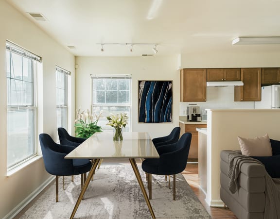A dining table with chairs and a kitchen with wood cabinets and stone counters at Horace Mann apartments and townhomes in Gary, IN