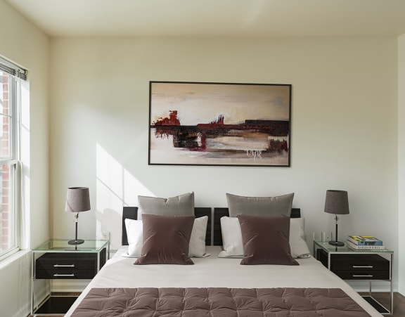 a bedroom at Beecher Terrace apartments with two windows and a bed with white sheets and pillows