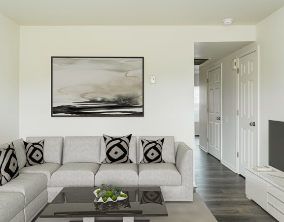 a living room with a couch, coffee table and tv stand with a painting hanging on the wall at Horace Mann Apartments and townhomes in Gary, IN