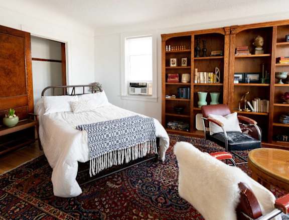 a bedroom with a bed and bookshelves     and a chair