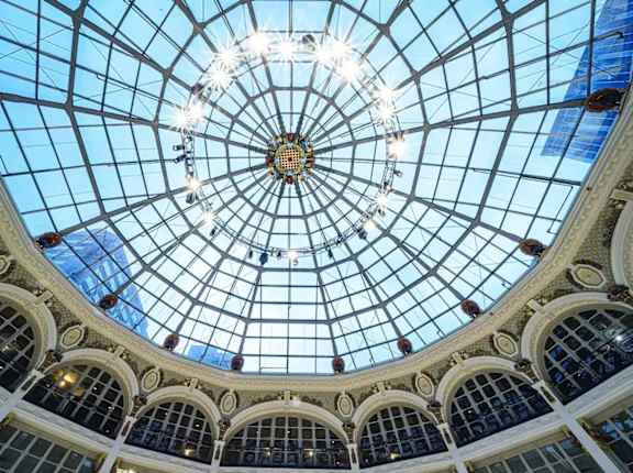 The image shows a beautiful glass dome ceiling with lights and arches.