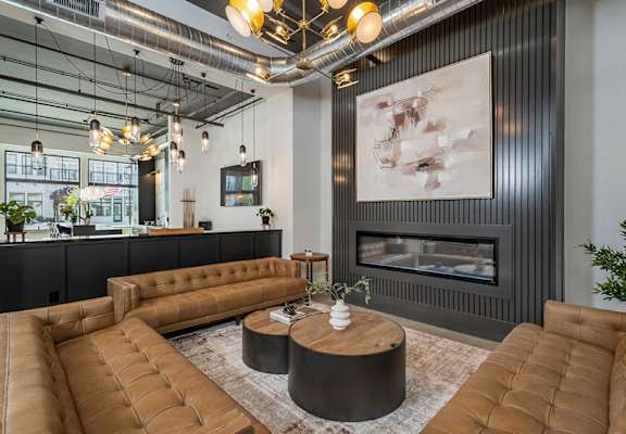 A modern living room with a fireplace and brown leather furniture.