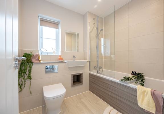 A bathroom with a toilet, sink, and a window.