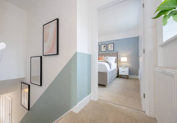 A bedroom with a bed, nightstand, and pictures on the wall.