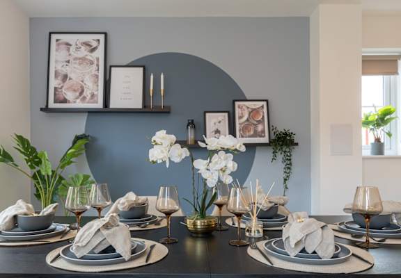 A dining table set with plates, glasses, and flowers.