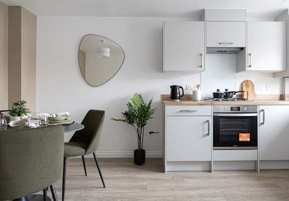 A modern kitchen with a dining table set for two.