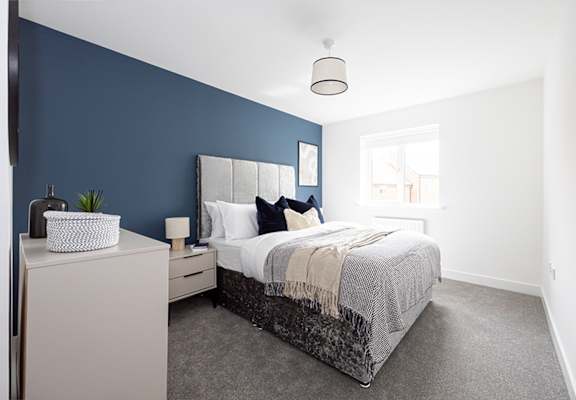 A bedroom with a bed, nightstand, and a plant.