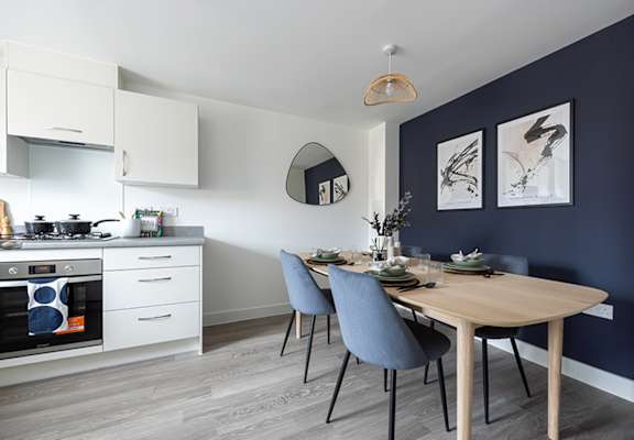 A modern kitchen with a dining table set for two.