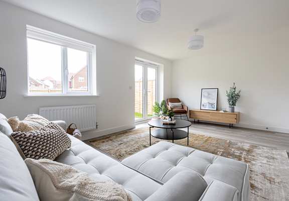 A living room with a white couch and a small table with a plant on it.
