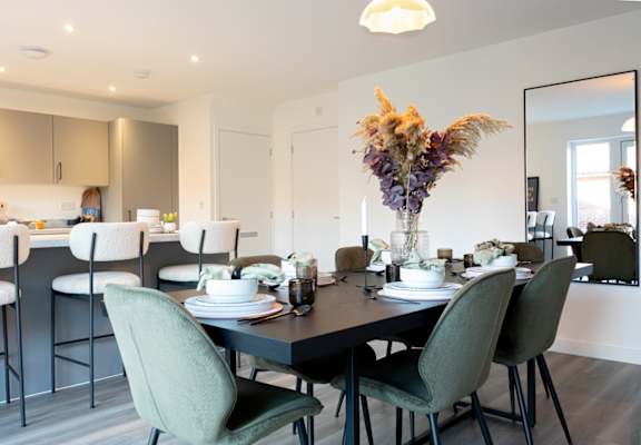 A modern dining room with a black table and green chairs.